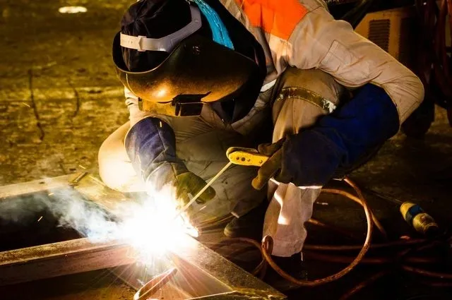A welder working on a piece of metal at night.